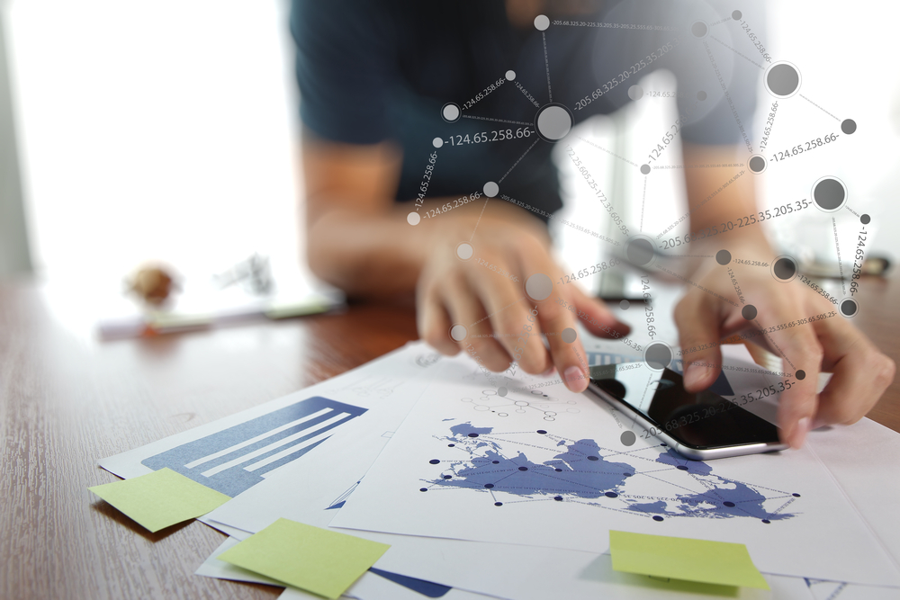 business documents on office table with smart phone and digital tablet and man working in the background business documents on office table with smart phone and digital tablet and man working in the background